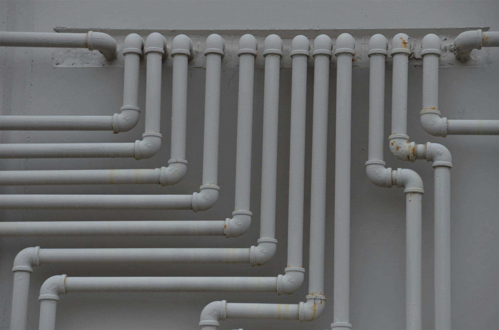 Rows of white water pipes mounted on a wall